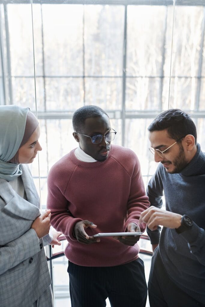 A group of coworkers discussing a project with a tablet in a spacious office.