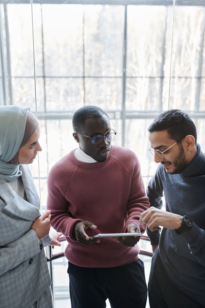 A group of coworkers discussing a project with a tablet in a spacious office.